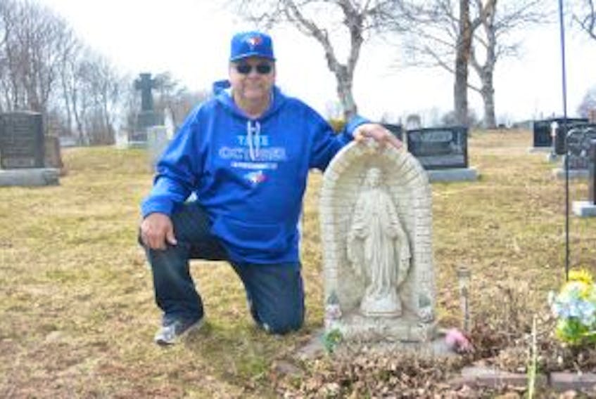 ['Eli Gallant with his mother’s tombstone in St. Paul’s Cemetery in Summerside. Several stones were vandalized recently. The Gallant family had managed to repair those belonging to their relatives by Monday afternoon.']