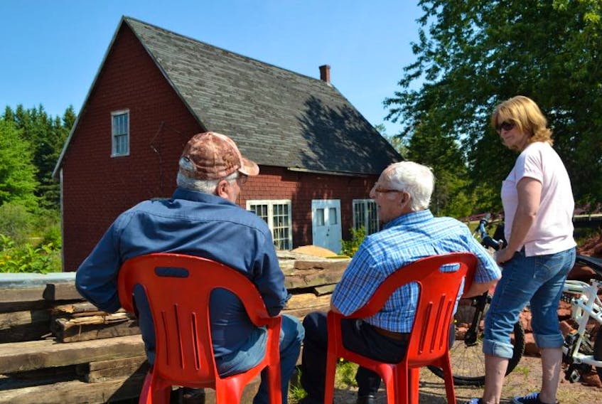 Warren Leard, center, Prince Edward Island’s last surviving miller, has a front row seat as he watches Leard’s Grist Mill  being raised Tuesday. Reminiscing with him are former neighbours Curtis MacPhee and Joyce MacPhee Bridges.