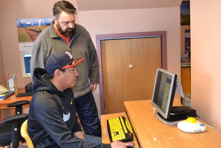 Thomas Ignacio, seated, gives Tignish-Palmer Road MLA Hal Perry a crash course on how to run multiple screens on the computer to vote for O’Leary for Kraft Hockeyville 2017. Perry coordinated a voting station in Tignish to facilitate high-speed voting for O’Leary.