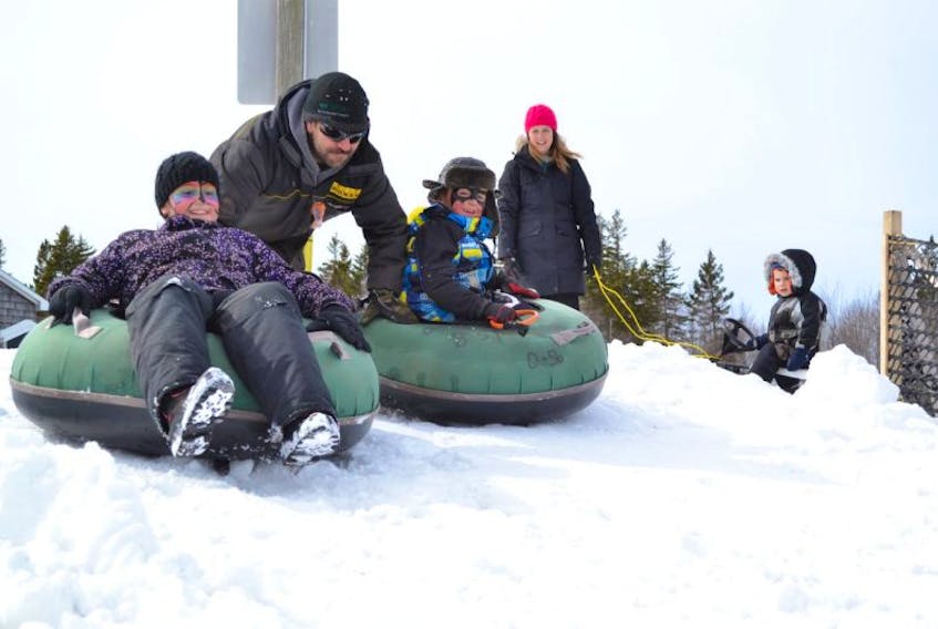 Keera and Jessie Gallant beam with anticipation as their father, Rodney gives them a push down the tubing hill at the Mill River resort Friday. Wednesday’s snowfall provided park workers with enough snow to move around and reopen the hill for the final days of March Break.