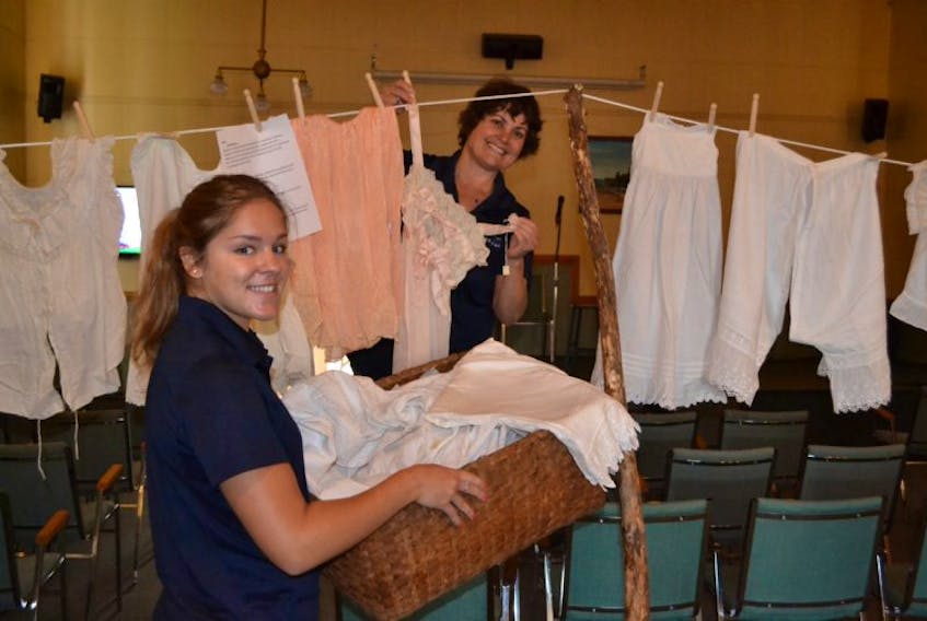 Alberton Visitor Information Centre guide Dena McHugh, foreground, helps co-worker Isabel Delaney load a clothesline with a display of women’s undergarments from the 1800s. They were brought out of storage at the Alberton Museum for the special display.