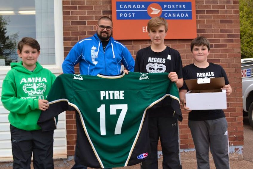 Coach Mitch Illsley and members of his Alberton Pee Wee A Regals hockey team from left, Brandon MacDongall, Ethan O’Brien and Ian O’Brien display the Regals jersey they’re sending off to Jonathan Pitre, an Ontario teenager undergoing complicated medical procedures in Minneapolis. The package will also contain a $10,000 donation for Pitre and his mother, the result of a special fundraising campaign undertaken by the Regals.