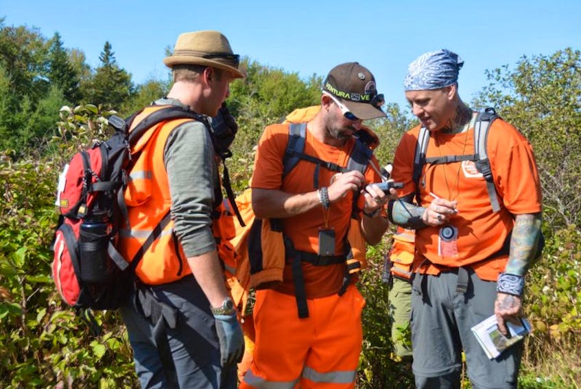 Troy Howatt, Chad Acorn, and the new team leader Stacy Chaisson find a potential clue in the dense foliage that may help to locate the three missing subjects at Trout River. 

