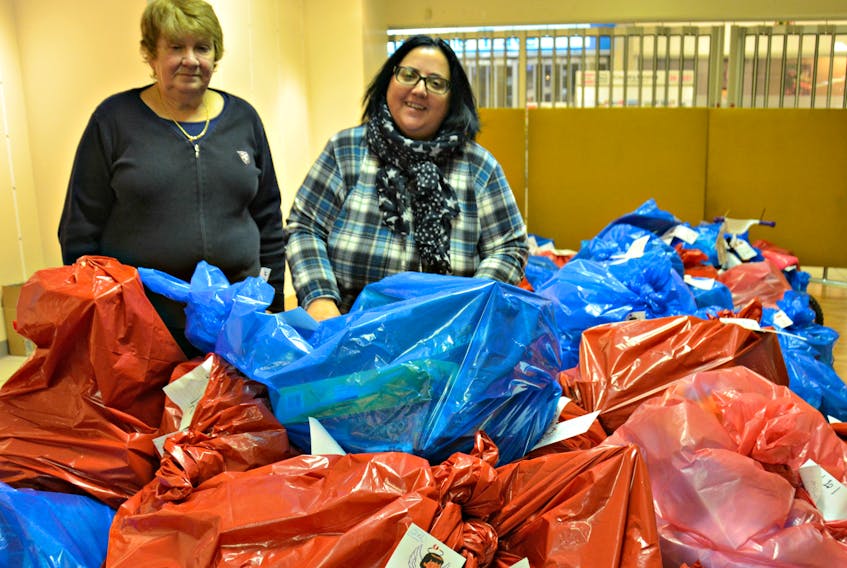 Volunteer Reta Owens, from left, and Captain Dolores Abbot, of the Salvation Army church in Summerside sorting donations into (blue for boys and red for girls) sacks that will be distributed to area families in need.

“I was one of nine children and I was the oldest and we were very poor. My mother was a single mom and we had nothing, very little food. If it were not for the community and the Salvation Army, we would not have had a Christmas or a Christmas dinner. Now as a mature adult it’s my time to give back,” said Owens.