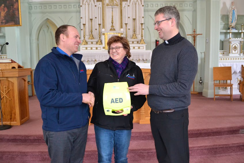 Daniel MacDonald left, Property and Finance chairman for St. Mark's Parish in Burton, and Parish Priest, Fr. Andrew MacDonald, accept a donation of an automated external defibrillator for the parish from Avis McDonald.