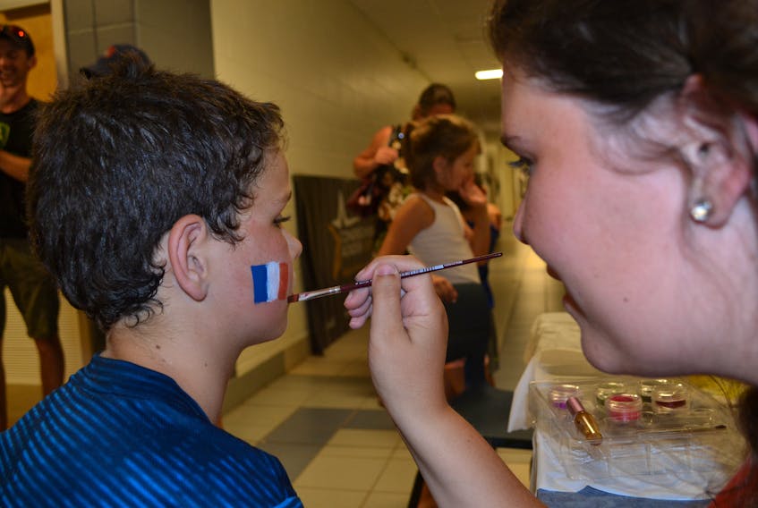 Megan Keough puts the finishing touches to a Acadian flag on Simon Doucette cheek during National Acadian Day celebrations at Centre Acadien de Prince-Ouest in Deblois Wednesday.