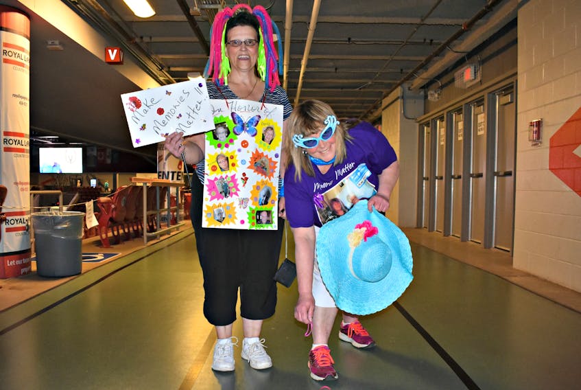 Corrine Arsenault, from left, and Gail DesRoches pick up an elastic band with each full lap made around the Credit Union Place indoor track as part of the Group Walk for Alzheimer’s on Saturday afternoon.