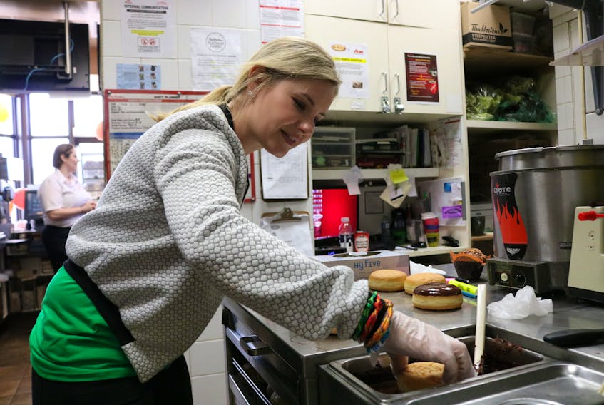Elisha Cuthbert glazes a Boston Cream Donut in the kitchen of the Kensington Tim Hortons. Cuthbert was at the establishment to volunteer for Camp Day.