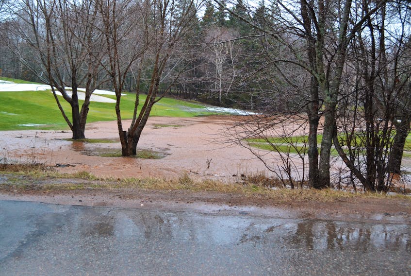 A ditch overflows along the Fortune Cove Road Saturday morning causing a stream to form across a fairway on the Mill River Experience Golf Course.