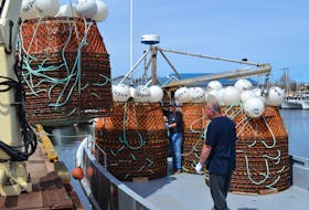 Jimmy Hardy, left, and Troy Gordon give a wide berth to a stack of crab pots being loaded onto Austie O’Meara’s Ocean Commotion fishing vessel Friday at Northport wharf.  Fishermen will set sail from harbours around the Southern Gulf at 12:01 Sunday morning to commence the 2018 snow crab fishery in Zone 12.
