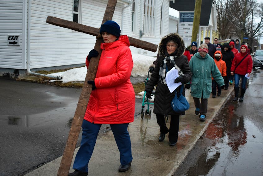 Norma McColeman carries a cross that's set against a bleak rain swept backdrop.