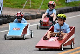 Cohen Poirier, from left, Hayden Ramsay, and Rowan Colwill feel the thrill of the derby hill as they race from the start to finish line.