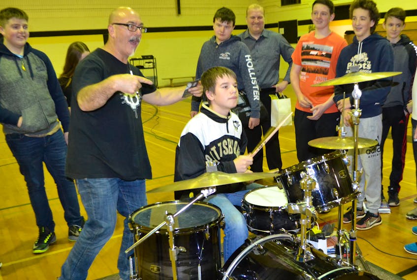 Mitch Dorge reacts as Hernewood student Jaxon Maynard gives beat to the motivational speaker's drum set.