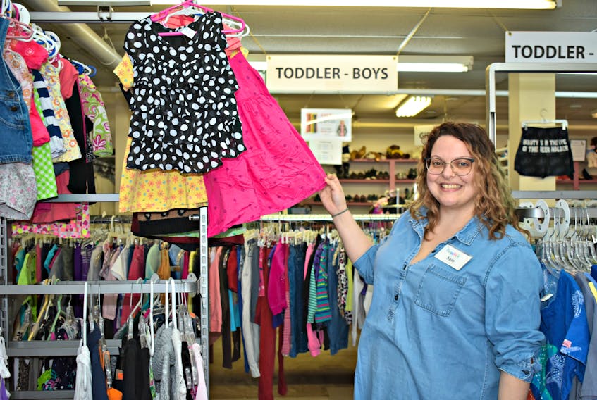 Samantha Fleischhacker picks through the clothes on a rack for toddlers that will soon be moved next door.
