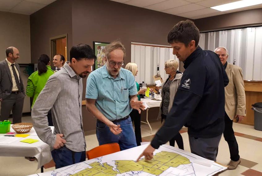Newly nominated Green candidates Jason Charette for O'Leary-Inverness (left) and Nick Arsenault for Evangeline-Misouche (right) examine electoral maps along with Boyd Leard, Green Party nominated candidate for District 1 (Souris-Elmira).