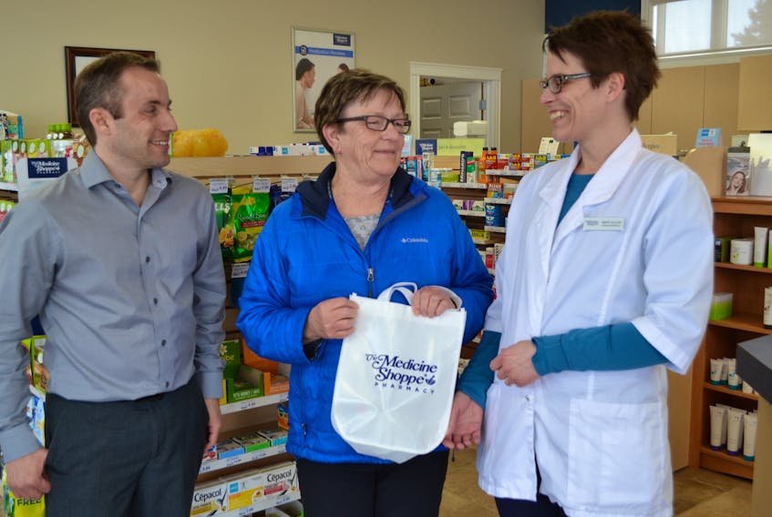 Andrew Ramsay, volunteer coordinator for the manors and hospitals in Alberton and O'Leary looks on as Esther Saunders accepts a Volunteer Rewards Program gift from Medicine Shoppe pharmacist Mary Ellen Rennie. Saunders volunteers about eight hours a week at Maplewood Manor.