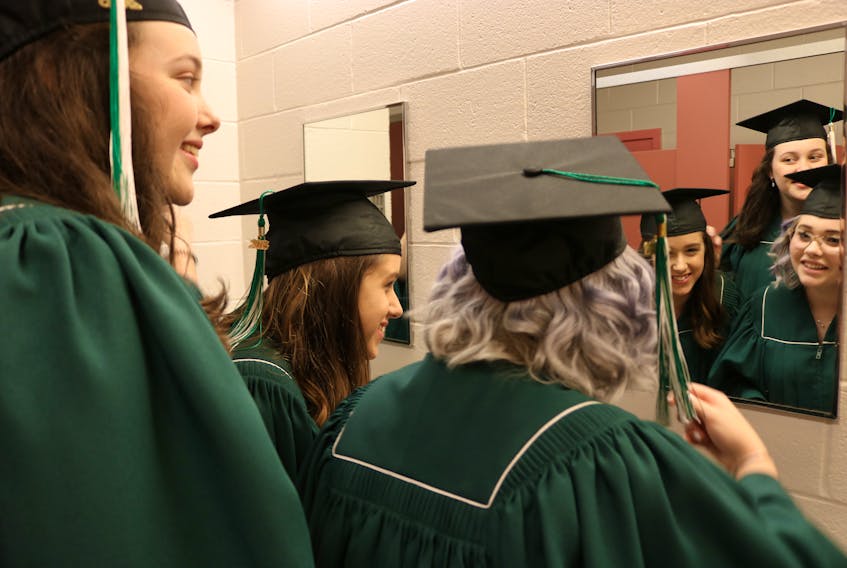 Bethany Spencer, left, Hannah Reeves, and Sher Wall do a final check before they walk across the stage and receive their high school diplomas.