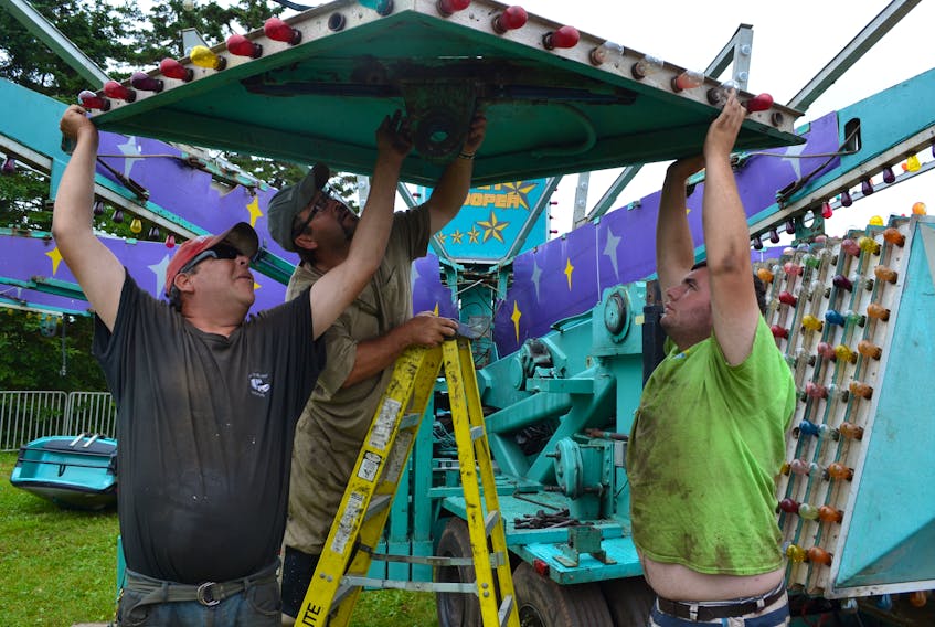 Hinchey’s Rides and Amusements workers, from left, Shawn Turgeon, Donald Francis and Daniel McLaren team up to assemble the midway’s Star Trooper ride. The midway is getting the rides set up in Alberton early in preparation for the July 26 to 28 Prince County Exhibition.