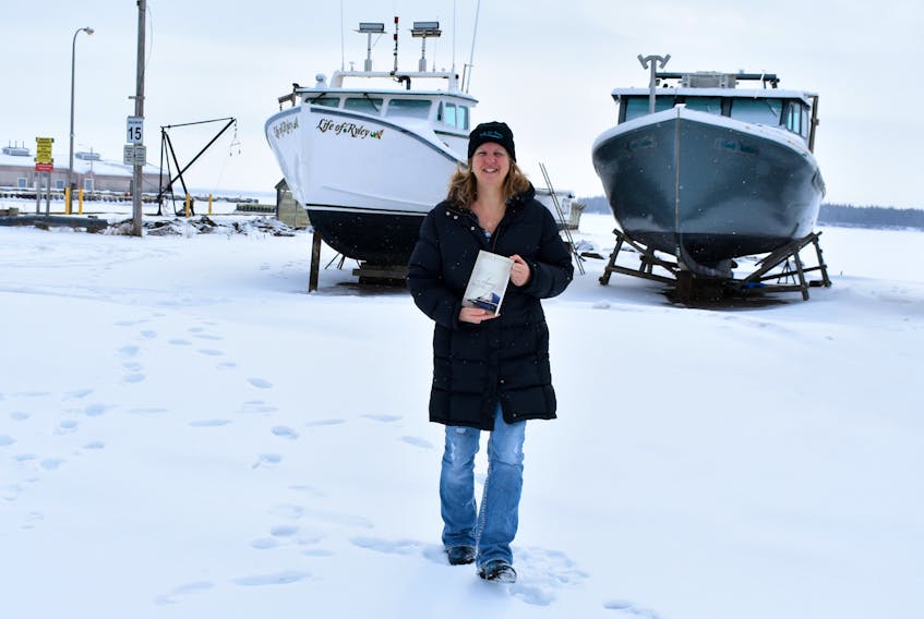 Susan Rodgers stands at the first filming location of ‘Still the Water,’ which will take place at the Summerside waterfront, in front of two fishing boats, with an ice-hockey game.