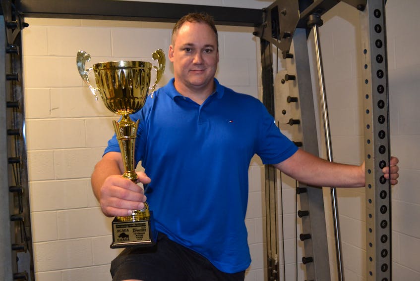 George Kinch displays the trophy he won for placing second overall in the masters division of the Canadian strongman championship last month in Waterloo, Que.