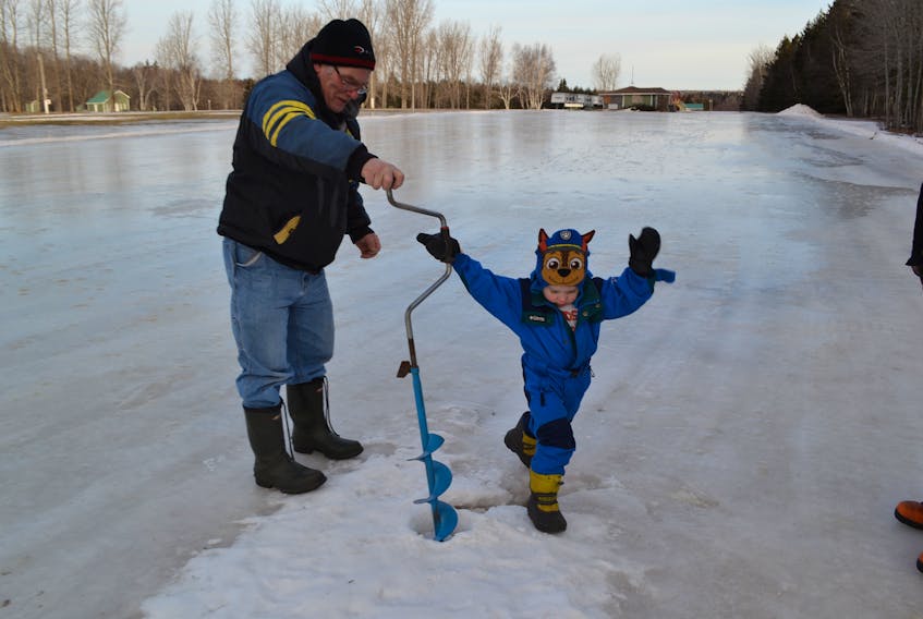 Gordon Dumville gets a hand from his four year-old grandson, Ben Lewis, in augering out a soft spot in the large skating patch members of the West Point Fire Department have prepared at Mill River Park for Saturday’s P.E.I. Pond Hockey championship. The soft spot was to be patched over and the whole surface subdivided into six hockey rinks for Saturday’s day-long competition.