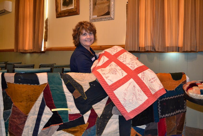 Isabel Delaney, visitor information guide at the Alberton Arts and Heritage Centre, displays a signature quilt made in 1892. Below it is a dark-patterned quilt from the George Gard estate which was donated to the Alberton Museum by Adele Heckman.