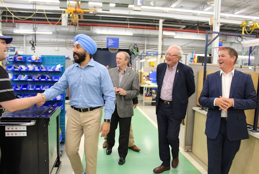 Federal Economic Development Minister Navdeep Bains, chats with an employee of StandardAero, during a walk-through of that company’s facility in Slemon Park with Egmont MP Bobby Morrissey, Premier Wade MacLauchlan, and StandardAero Summerside president, Jeff Poirier.