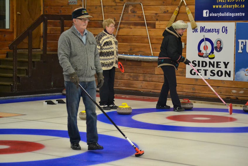 Harvey Holm calls a shot on one ice while fellow Alberton stick curler Audrey Callaghan watches as Cornwall curler Gloria Clarke calls a shot on an adjacent ice. Stick curlers, when they are playing skip, can sweep from their hog line in. Their teammates deliver their stones using a delivery stick.
