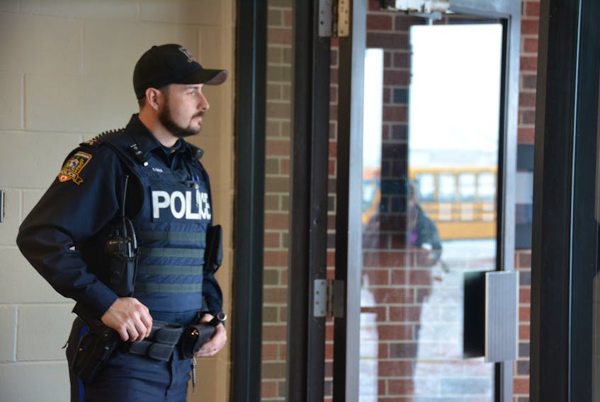 Summerside Police Services Const. Tyler Shea keeps an eye on one of the main entrances to Three Oaks Senior High School recently.