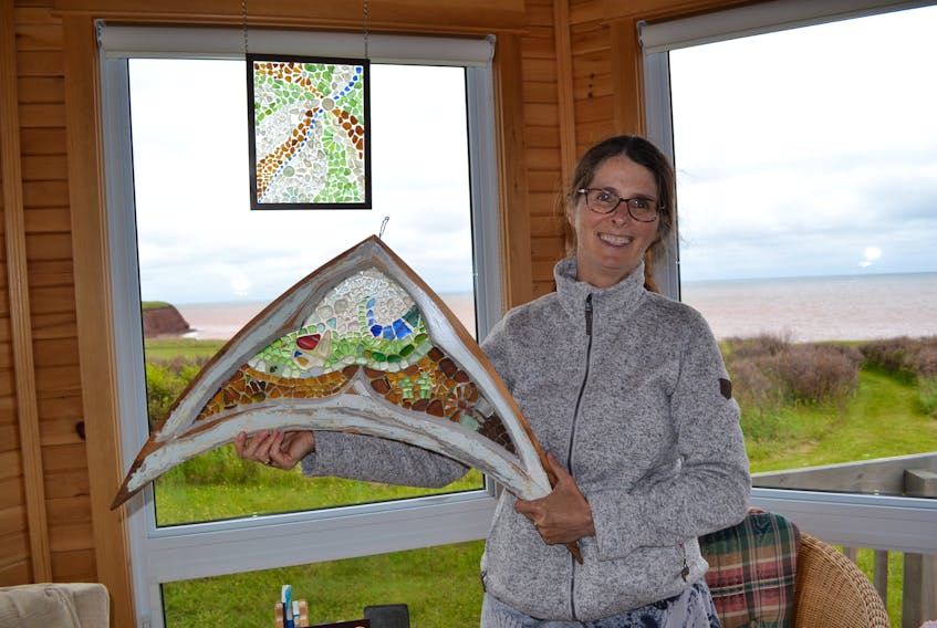 The first sea glass mosaic she ever created hangs in the background as Jackie Trimper displays one of her more recent creations.