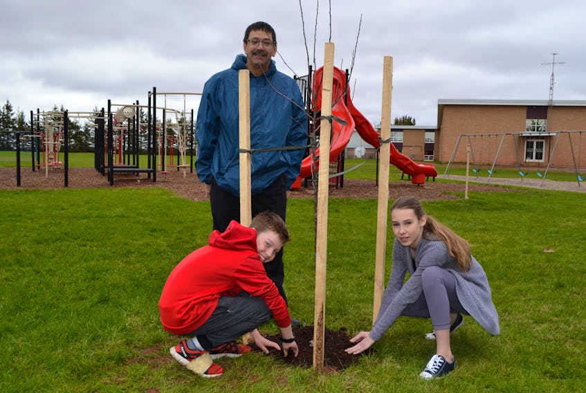 Bloomfield Elementary School students Nolan Cahill and Erica Sweet check with their teacher, Paul Muise, on how well the foraging wall they helped establish on their school’s playground is performing.