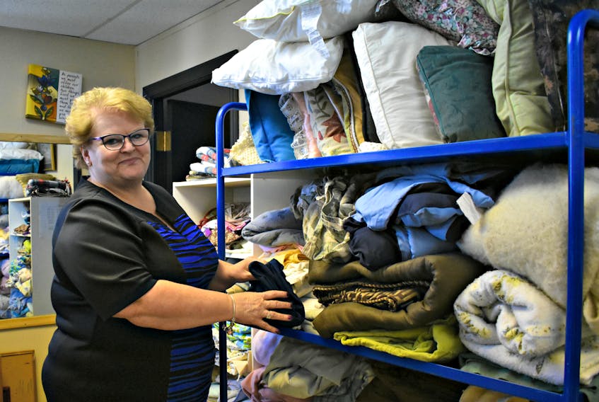 Free Store owner Belinda Woods folding items of warm bedding.