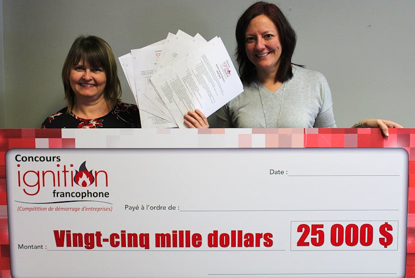 Velma Robichaud, left, coordinator of the new Francophone Ignition Contest, shows the entry forms of her eight contestants. On March 16, one of these eight names will be written on this big $25,000 cheque being held with Robichaud by RDÉE PEI executive director Bonnie Gallant.