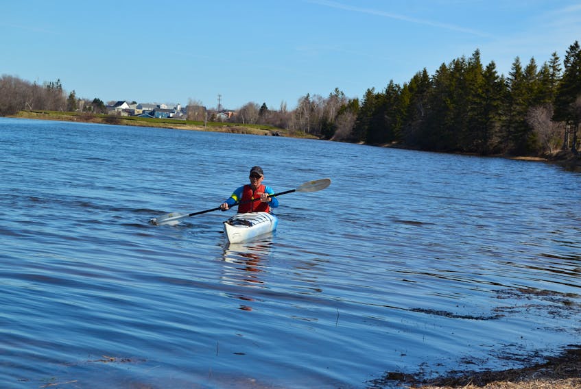 Northport resident Peter Bolo kayaks through Alberton Creek below his home. The Alberton lagoon is in the background. Area residents expressed concern a planned lagoon upgrade would deny them summertime use of the stream. The town has since decided to put off the project until the fall.