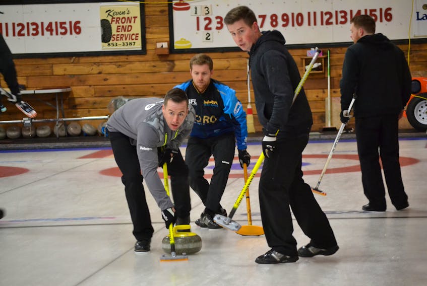 Steve Burgess, left, and Robbie Doherty look down ice to their skip, John Likely, for instructions on whether to sweep a rock thrown by their mate, Anson Carmody.