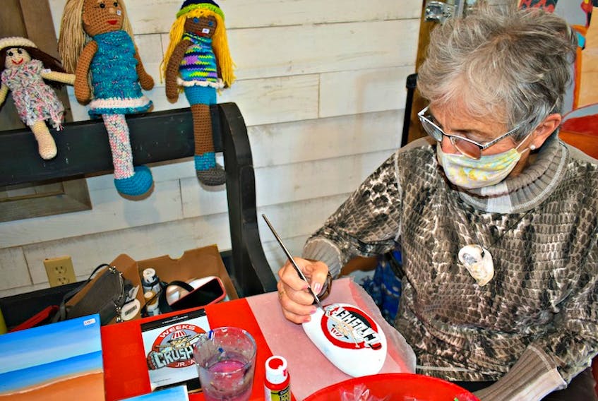Donna Nicholson paints a hockey image taken from a photograph onto a rock she collected on a nearby beach. "People give me images, and I paint them on rocks which can be used as garden ornaments or even as a door stopper," she said while showcasing painted shells, handmade cards, as well as rag dolls that were made by her sister, Carole Sentner.