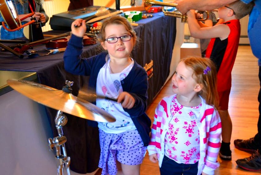 Kinley Jeffery, 4, (left) confidently tests her skills on the cymbal that’s part of a drum kit while her sister Kaydence, 2, laughs at the loud metal percussion sounds.