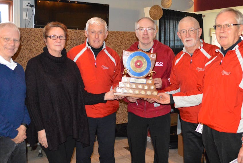 Curl P.E.I. vice-president Craig Mackie, left, and Crapaud Community Curling Club president Vivien Sherren offer congratulations to the 2019 P.E.I. men’s masters curling champions. Team members are, third from left: Lou Nowlan, skip; David MacFadyen, third stone; Earle Proude, second stone, and Alan Montgomery, lead.