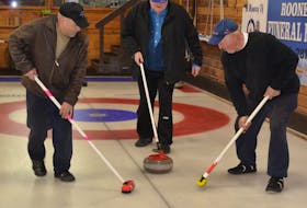 Eddie Bernard, left, and John Vincent prepare to sweep Walter Callaghan’s stone during a practice at the Western Community Curling Club. All members of a team skipped by Roger Gavin use a delivery stick to send their curling stones down the ice.