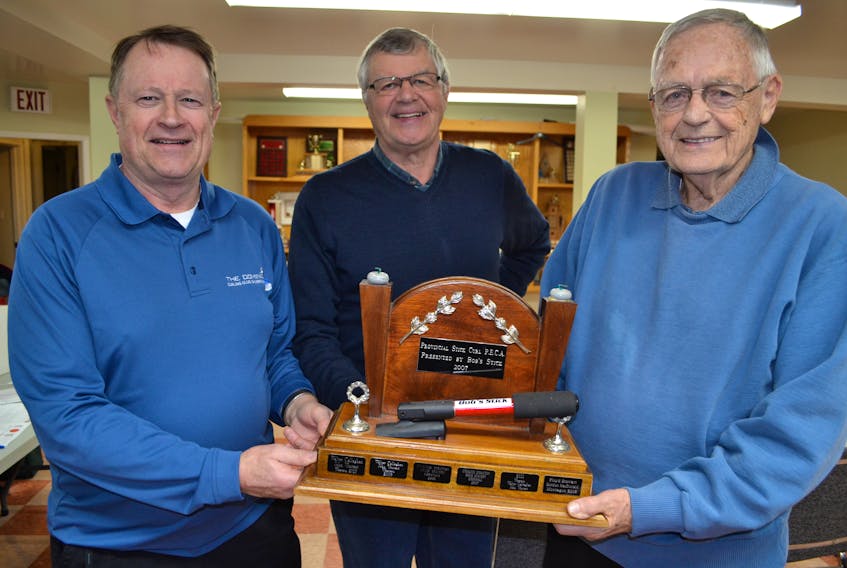 Ernie Stavert, centre, co-ordinator for the P.E.I. provincial stick curling championships, presents the Open Division championship trophy to Barry Craswell, left, and Sterling Stratton. This is their third provincial title together. Stratton also has two provincial titles to his credit with Stavert.
