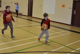 Colton Bridges and Emily Coughlin dribble the ball during a drill for the Miscouche Consolidated School basketball teams. In the background is coach Nicole Martin.