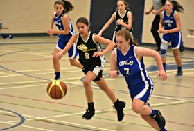 The Summerside Intermediate School (SIS) Owls’ Reghan Betts, 7, and Victoria Zakem, 9, of the Queen Charlotte Coyotes race to a loose ball during action in the 42nd annual Glenn Edison Memorial basketball tournament at SIS on Saturday.