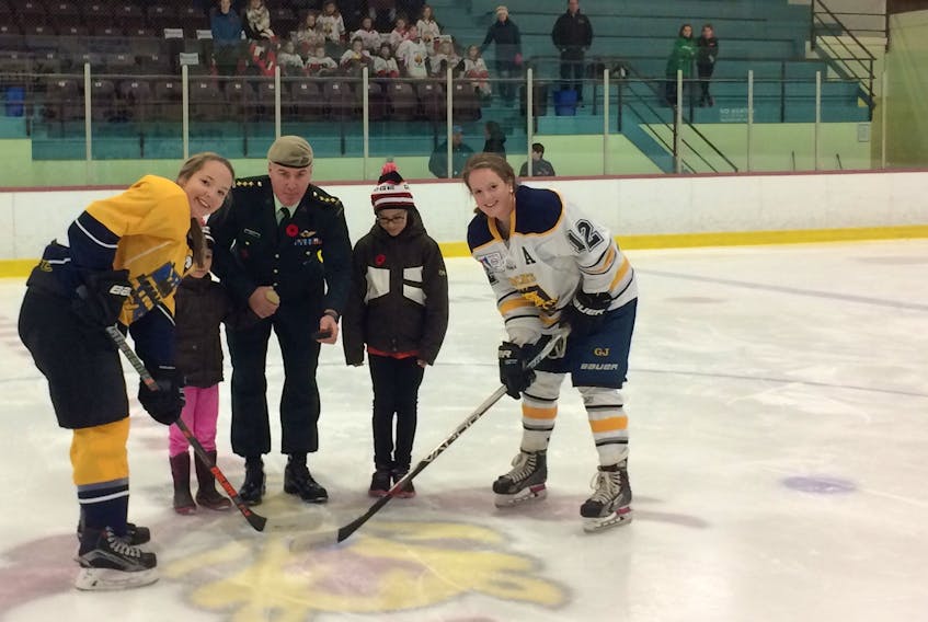 Capt. Danny Kelly, accompanied by his daughters Meghan and Mary, drops the puck for the opening faceoff of Friday night’s P.E.I. Midget AAA Female Hockey League game at the APM Centre in Cornwall. Captains Jacy MacMillan, left, of the Kings County Kings, and Makayla Larsen of the Mid-Isle Wildcats take the draw. The Wildcats held a pre-game ceremony to mark Veterans’ Week 2017.