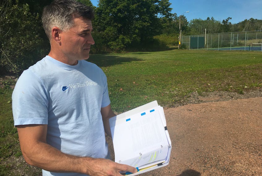 Matthew Brewer looks over plans for a proposed playground on the site of the former town hall building in Parrsboro. For three years, Brewer and a group of 40 volunteers has been working toward making the playground near the downtown a reality.