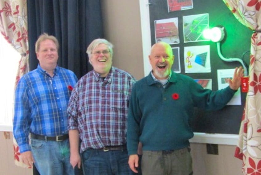 Rob Bentley (centre), chairman of the Parrsboro Band Association board, is flanked by treasurer Johannes Hiesberger and Bruce McCulloch in celebrating the near-completion of the installation of solar panels on the roof of The Hall in Parrsboro. Hiesberger and McCulloch were instrumental in getting the project’s financing in place.