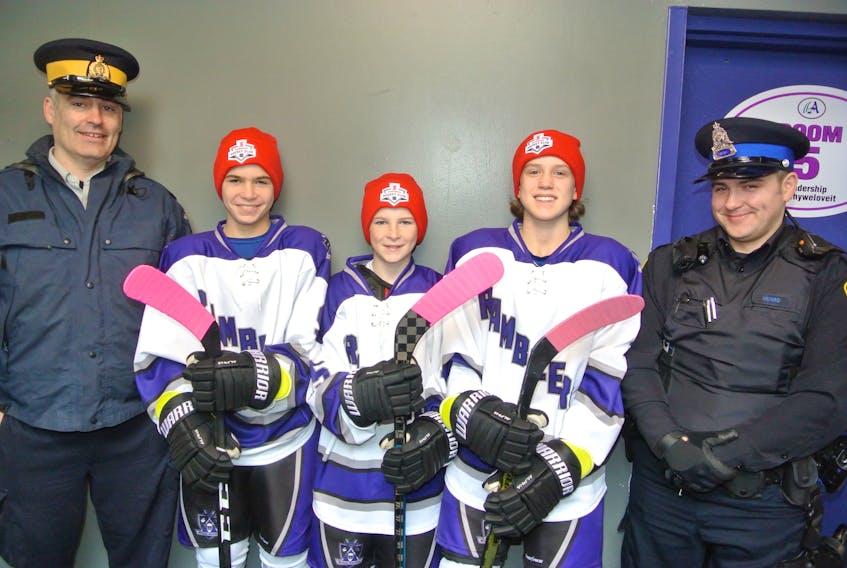 Richard Harvey of the RCMP (left) and Charlie Munro of the Amherst Police Department join Cumberland County Scotiabank Peewee AAA Ramblers Kieran Sears, Brady Stack and Reece MacDonald in marking the launch of Hockey Nova Scotia’s Pink Tape Campaign.
