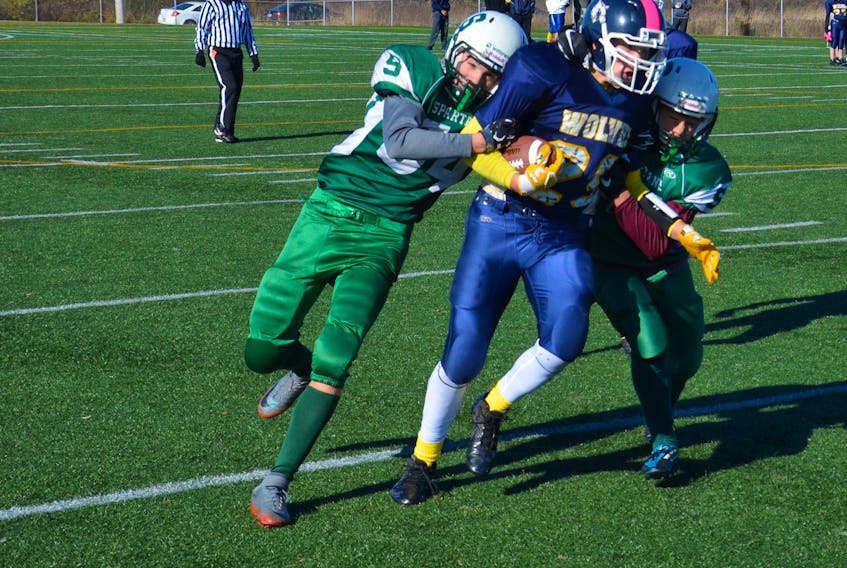 Tyler Newson attempts to fight through the tackle attempts of the Summerside Waterwise Spartans’ Breton Brown, left, and Kieran Arsenault during Saturday afternoon’s Ed Hilton Bowl at Eric Johnston Field in Summerside. Jason Simmonds/Journal Pioneer