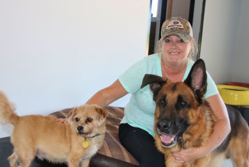Trish Sproule sits down for a moment with Tailgate, left, and Pilot. She’s opened Pilot’s Doggie Daycare on Salmon River Road, at the former All My Pets premises.