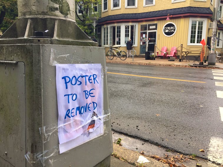 A lamp pole across from Coburg Coffee on Coburg Road spotted with a note that read POSTER TO BE REMOVED on Monday, Oct. 5, 2020. Below the note, there appeared to be a poster that blamed China for the global COVID-19 pandemic.