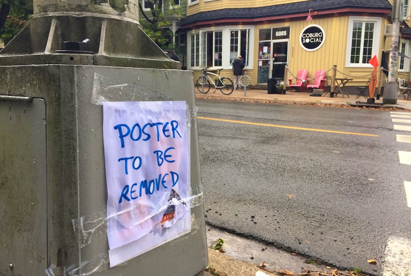 A lamp pole across from Coburg Coffee on Coburg Road spotted with a note that read POSTER TO BE REMOVED on Monday, Oct. 5, 2020. Below the note, there appeared to be a poster that blamed China for the global COVID-19 pandemic.
